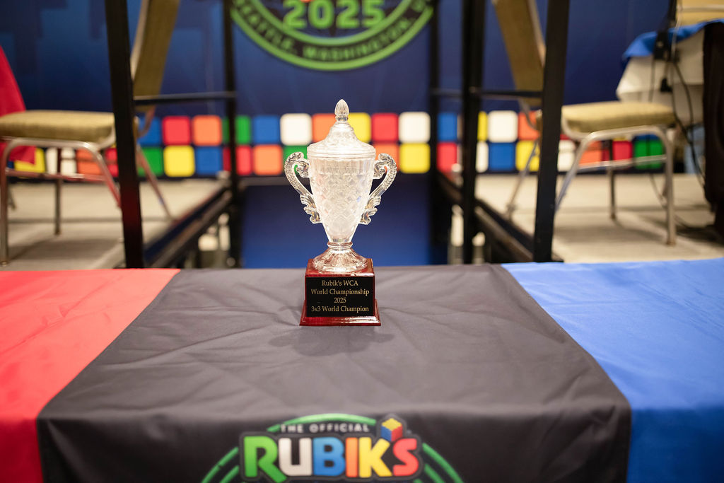 A trophy on top of a table with a banner which reads "Rubik's WCA World Championship 2025"